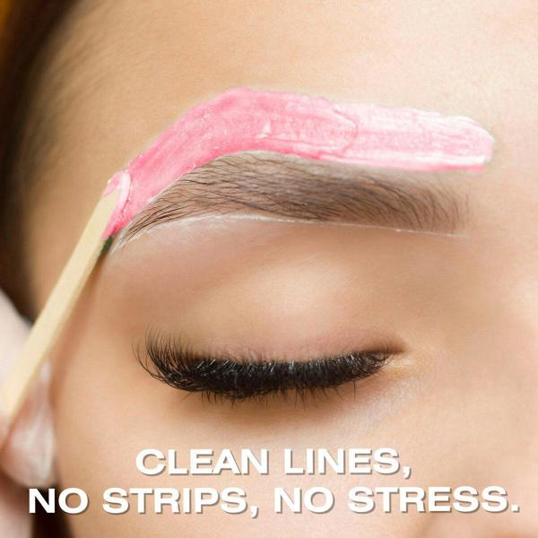 Close-up of Rose Go Smooth Stripless Hard Wax Beads (100g) by Rio being applied to an eyebrow with a wooden stick. The person’s eye is closed, with the text: CLEAN LINES, NO STRIPS, NO STRESS.