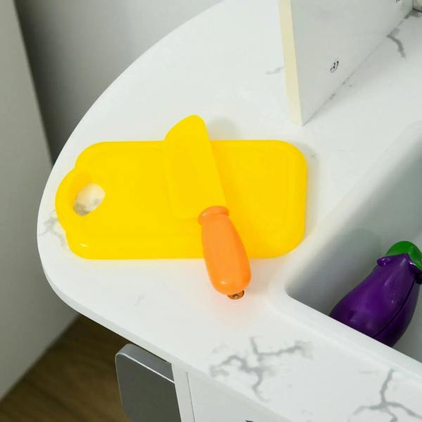 White toy kitchen counter with yellow cutting board, orange tool and purple produce