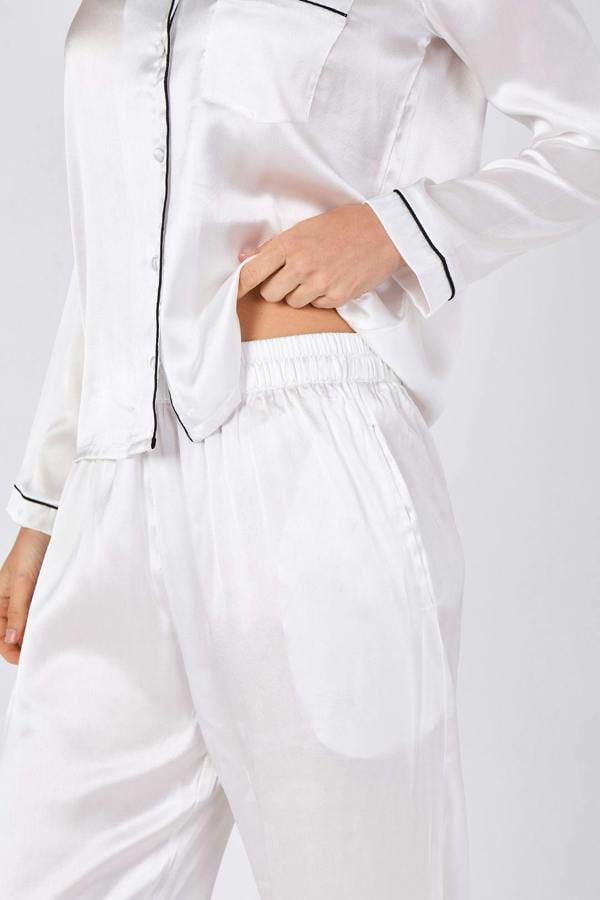 White satin pajama set with black piping on a white background