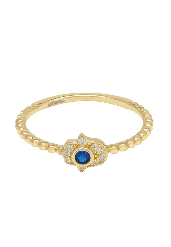 Gold ring with a blue gemstone and clear gemstone accents on a white background
