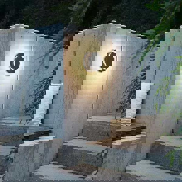 black LED outdoor wall lamp mounted on a concrete wall next to some steps