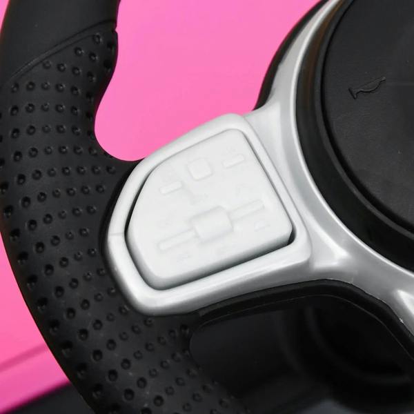 White foot pedal on pink kids ride-on car, black textured floorboard close-up.
