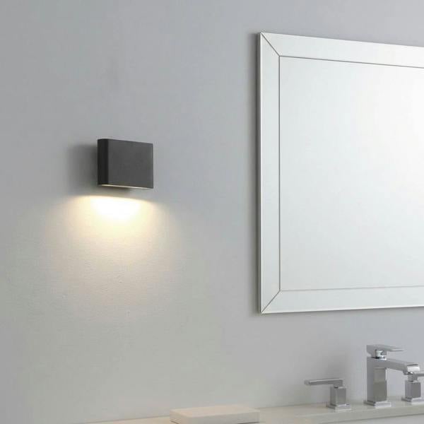 black LED bathroom sconce mounted on the wall of a bathroom next to a mirror 