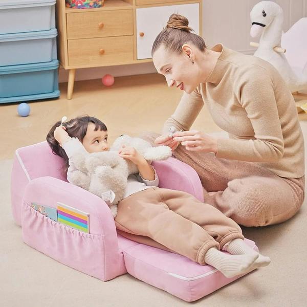 Pink toddler sofa bed with child sitting on the padded seat in an open lounging shape