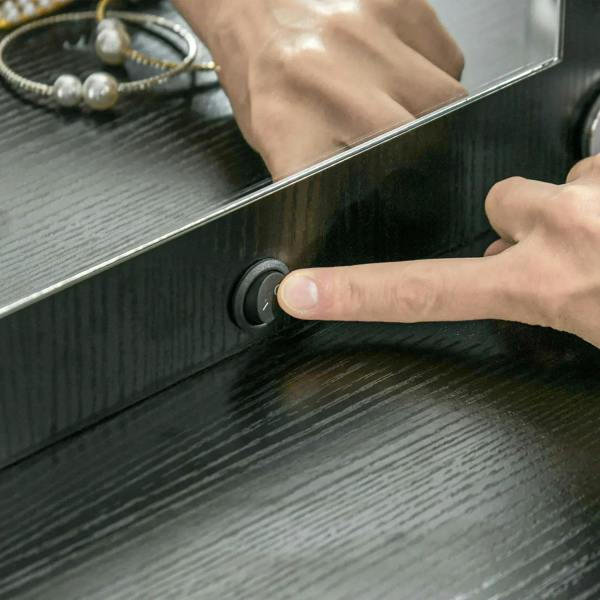 Black vanity drawer front with round knob and user hand gripping the drawer pull