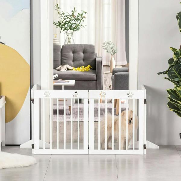 White wooden pet gate with vertical bars and paw-print panels, protecting a small dog