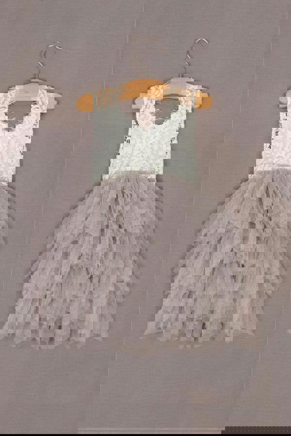 Children's dress with lace top and ruffled skirt on a hanger against a gray background