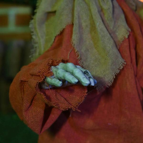 Halloween scarecrow decoration doll hand holding gray foam bones in orange fabric