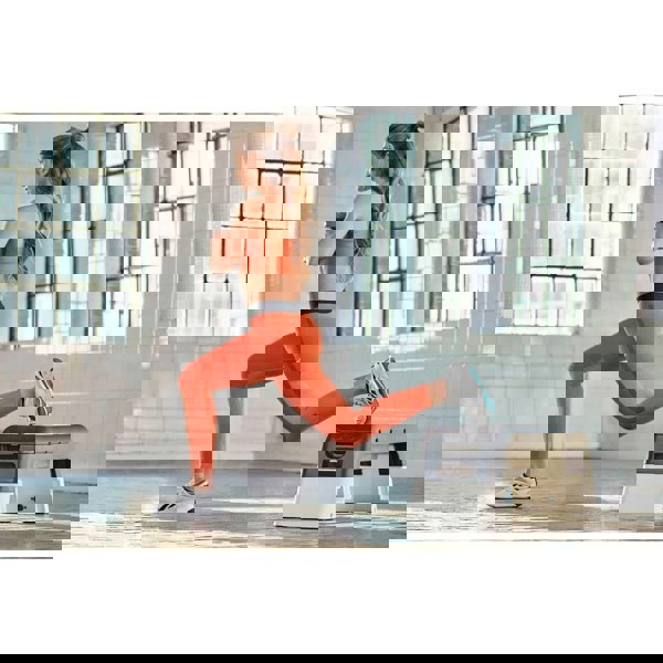 Woman performing lunges using a Reebok Deck - Home Workout - White