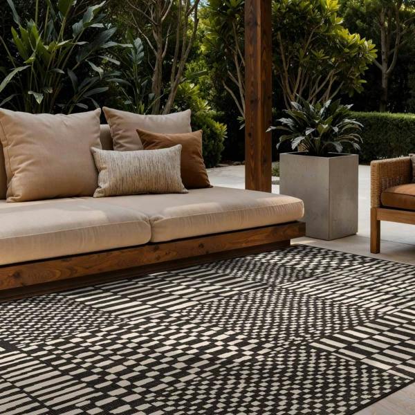 Outdoor seating area with a patterned rug, cushions, and plants.