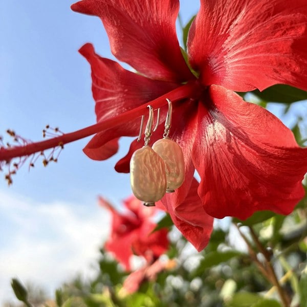 Elegant rectangle pearl drop earrings against a vibrant hibiscus flower.