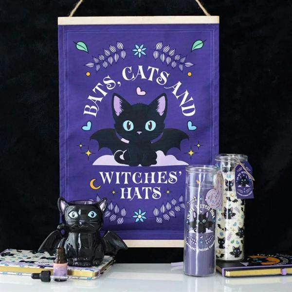 Lavender tube candle with witch cat design on clear glass cylinder, on display