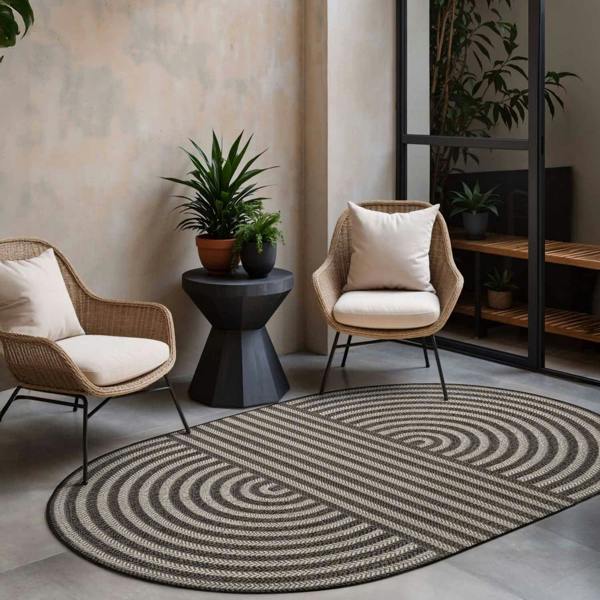 Living room with wicker chairs, a round rug, and decorative plants.