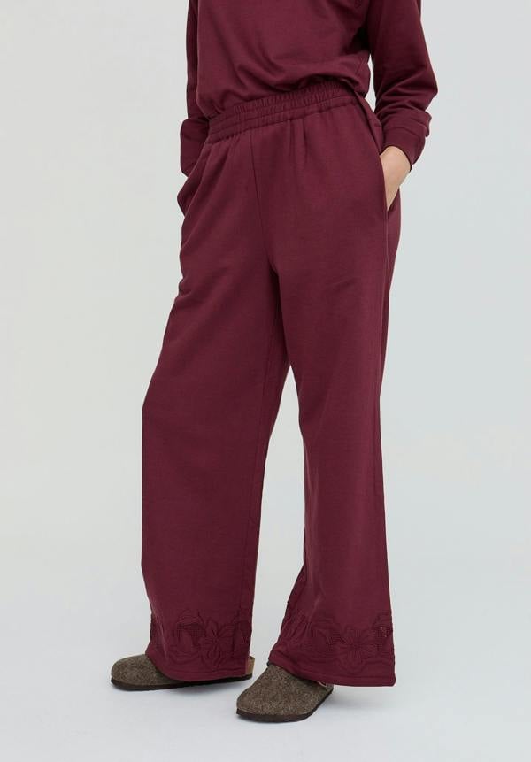 Maroon pants worn by a person on a white background