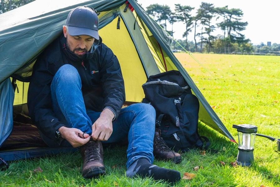 A walker puts his boots on in the OLPRO Hawford Lightweight 2 Person Tent.