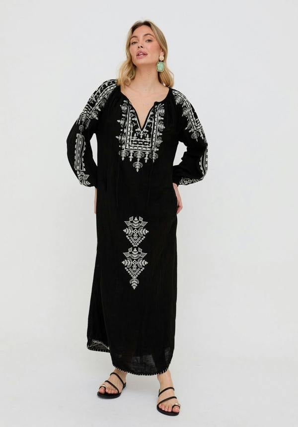 Woman wearing a black dress with white embroidery on a white background