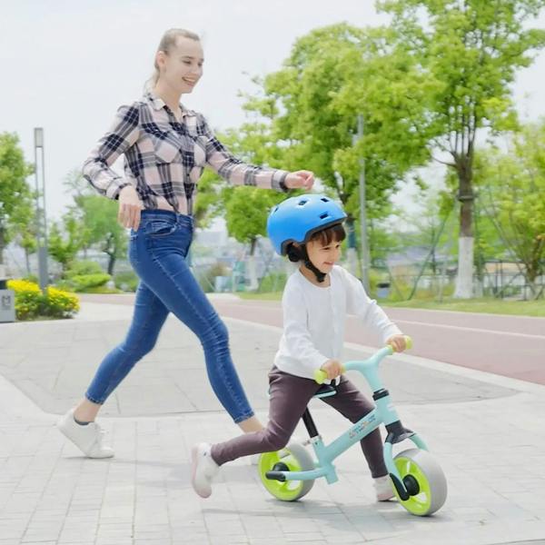 Young rider on a light green balance bike with lime wheels moving on pavement