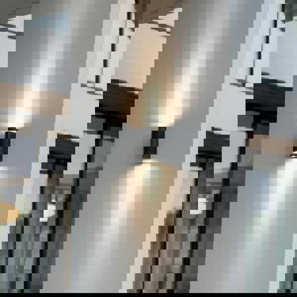 black outdoor up down light mounted on a white wall outside a modern home