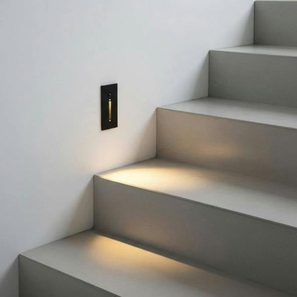 black sensor light for the stairs mounted in a white wall alongisde an indoor staircase 