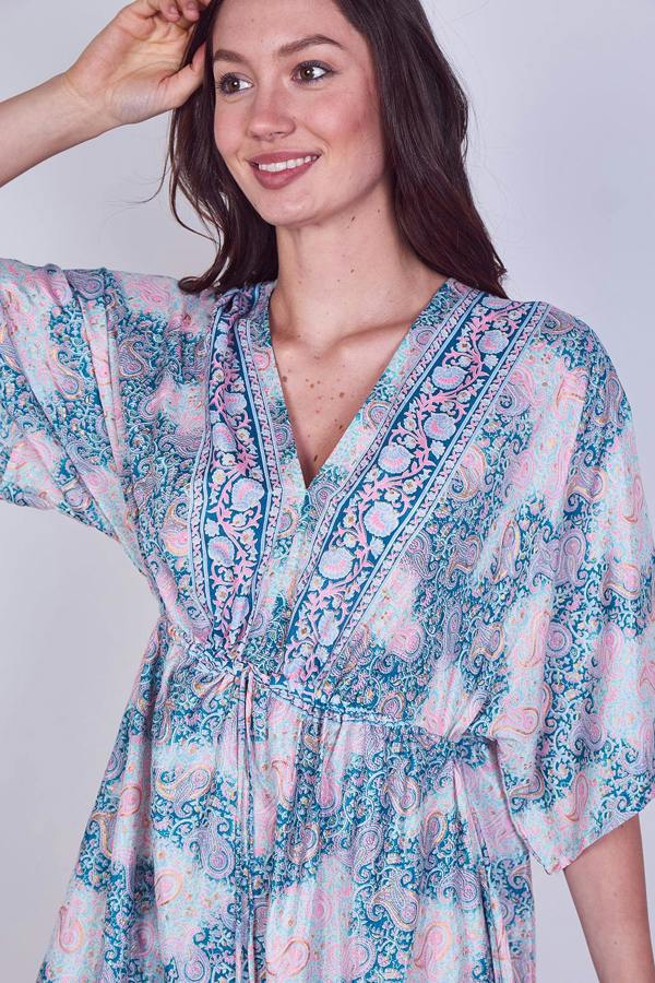 Woman wearing a colorful patterned dress against a plain background