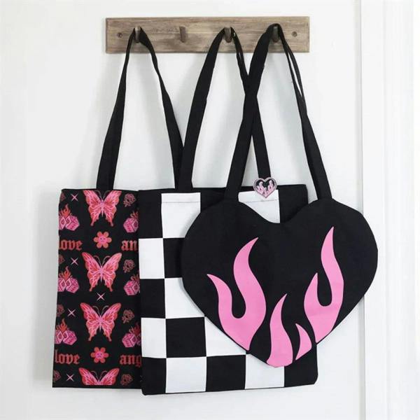 Black and white checkerboard tote bag with flaming heart enamel pin badge among other totes