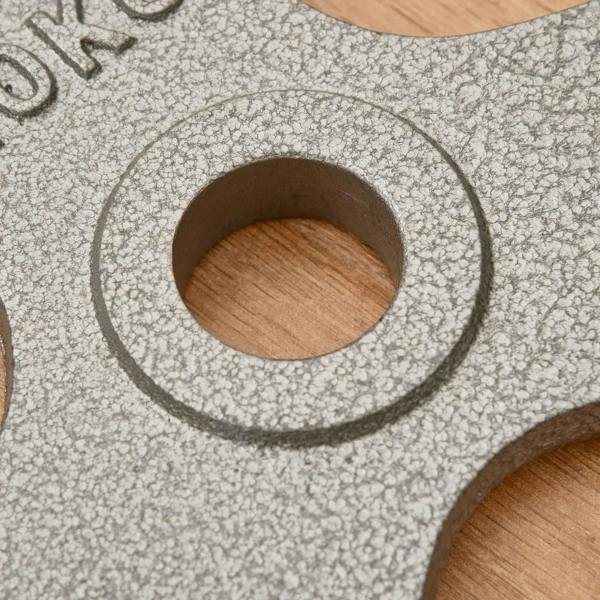 Close-up of cast iron weight plate center hole, speckled gray texture