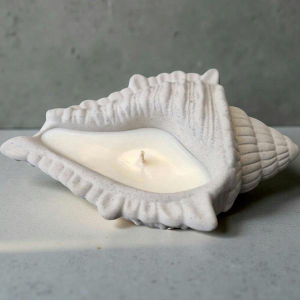 White ceramic shell with a candle inside on a gray surface