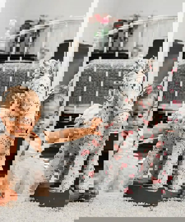 little girl in nursery room sat with floral printed horse