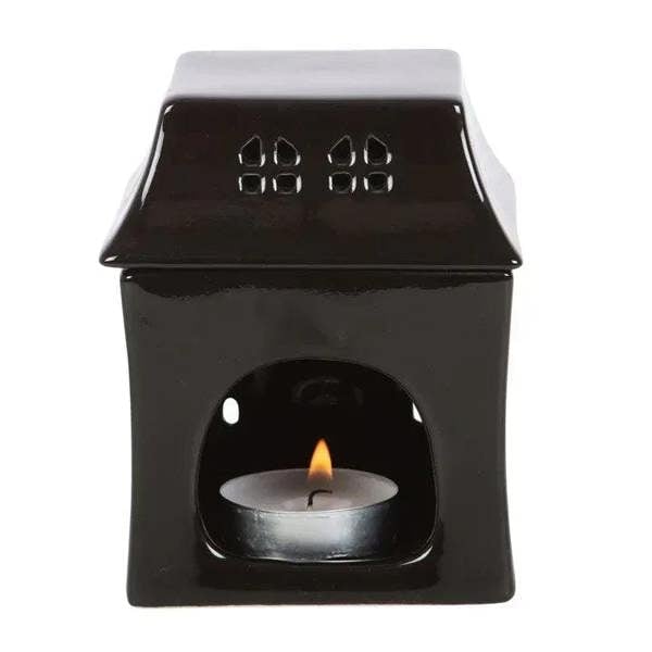 Black haunted house oil burner with candle flame in central opening