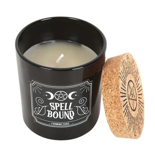 Black candle jar with lit wick, cork lid placed beside it and white label