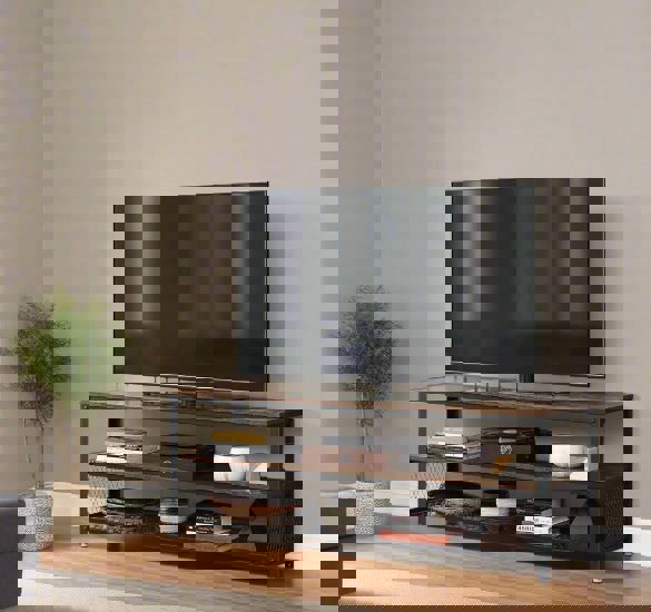 TV on a wooden stand against a beige wall with a plant to the left.