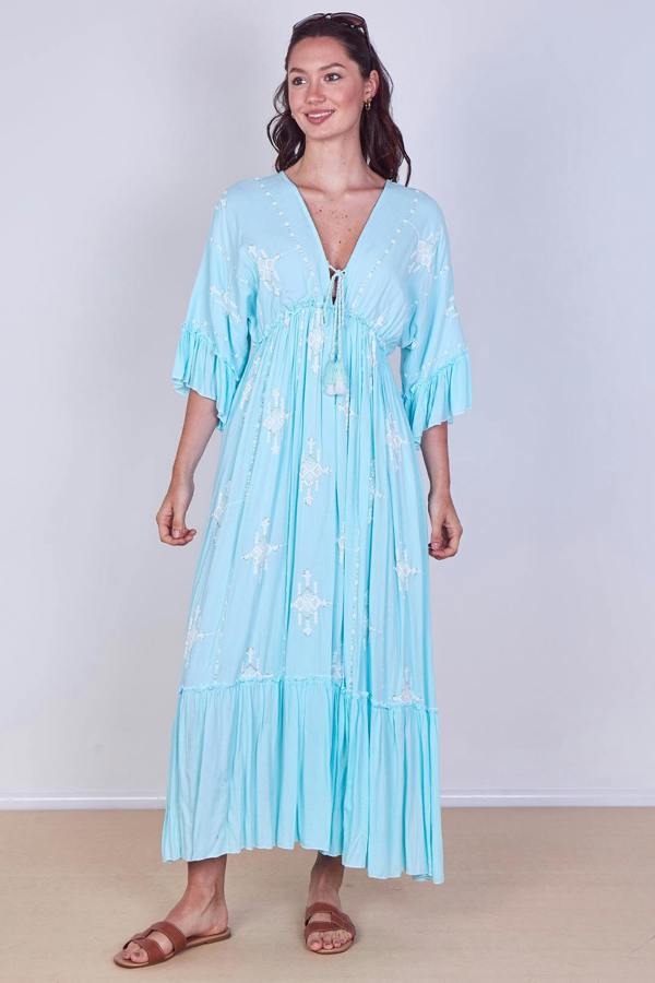 Woman wearing a light blue dress with star patterns on a plain background