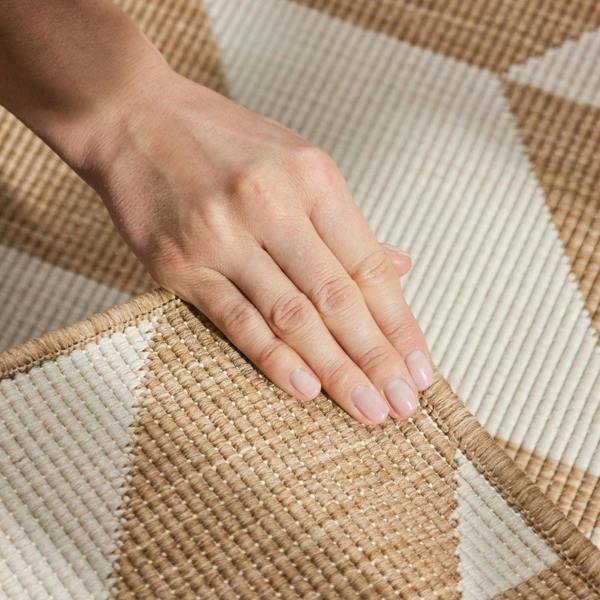 Hand touching a woven beige and white rug