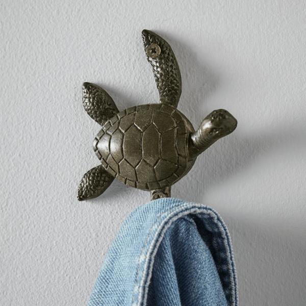 Antique bronze cast iron turtle wall hook mounted on a grey wall holding a blue denim jacket.