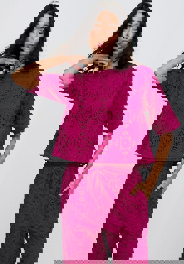 Woman wearing a magenta lace outfit on a white background