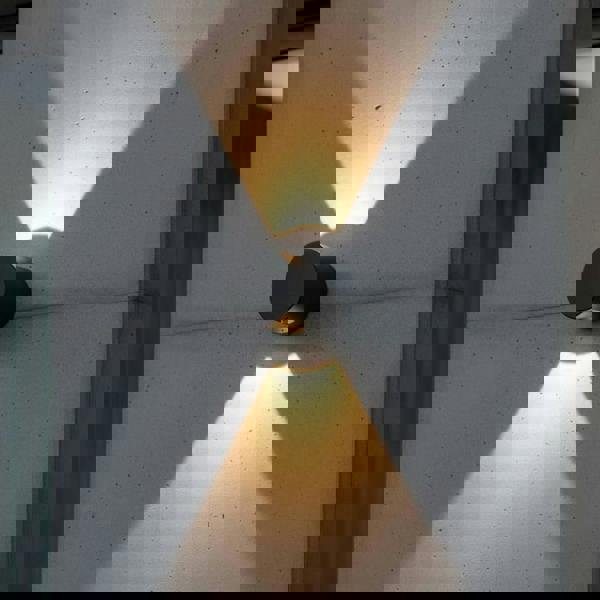 black outdoor up down wall light installed on a concrete wall outside a modern home