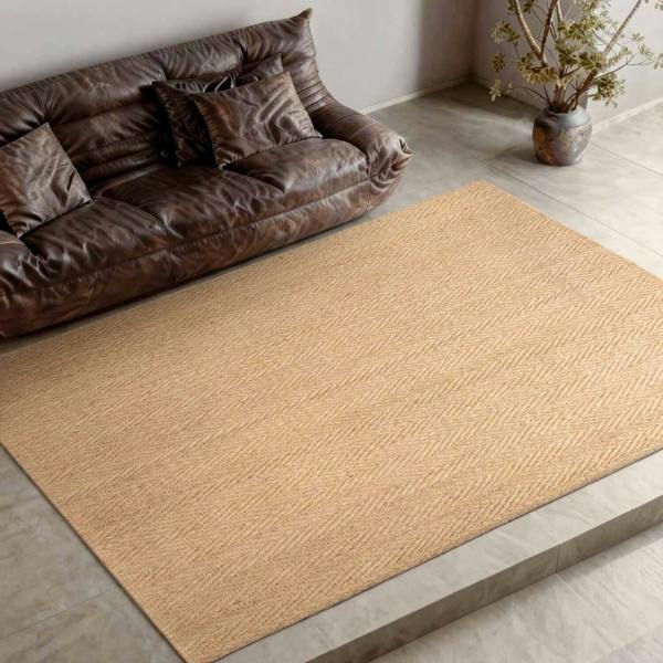 Brown woven rug on a wooden floor with a brown sofa and plant in the background.