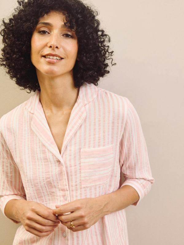Woman wearing a pink striped pyjama shirt against a plain background