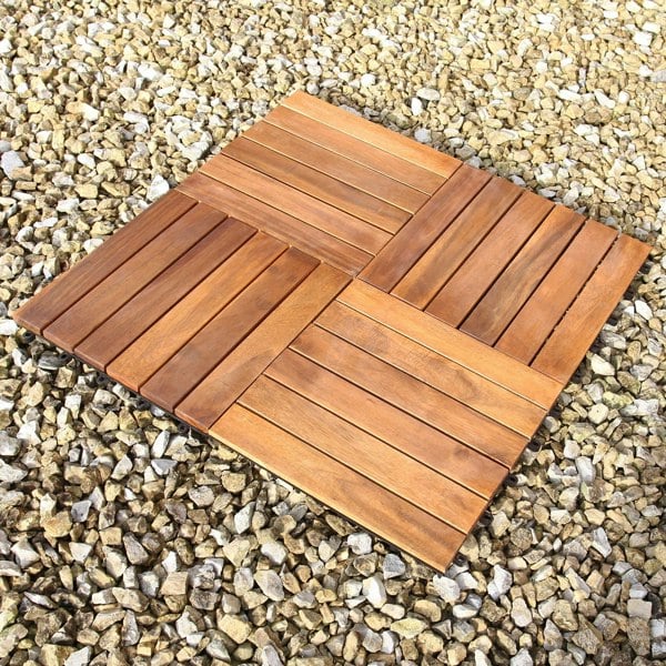 Natural wooden decking tiles arranged in a square pattern, showcasing rich brown tones and smooth, polished surfaces on a gravel background