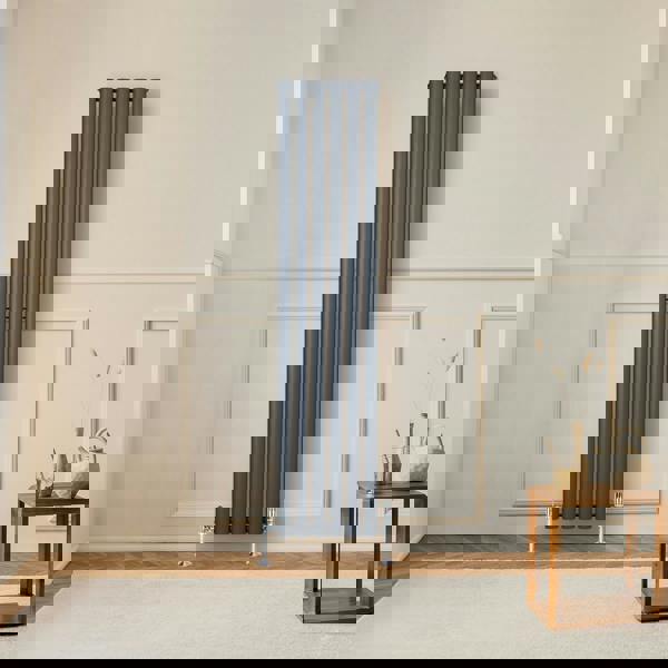 Oval single column radiator in anthracite grey, 1600 x 360mm, mounted on a wall, complementing a modern interior with wooden flooring