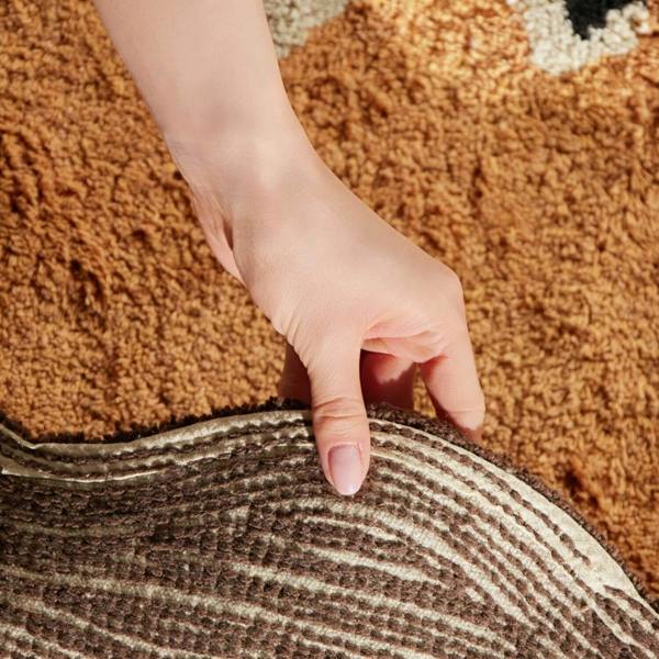 Hand pressing down on a textured doormat with a carpeted floor underneath