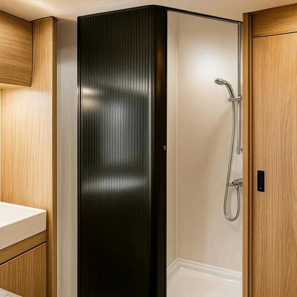 Sleek black Tambour shower door with vertical ribbed texture, set in a modern bathroom with warm wood accents and a clean shower space