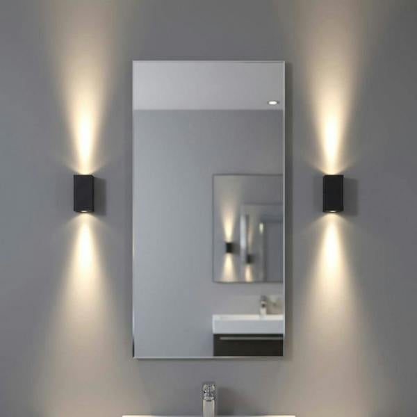 modern black bathroom sconce mounted either side of a mirror in a bathroom