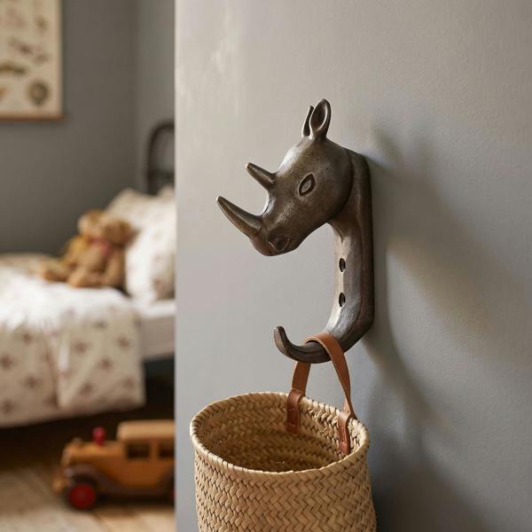 Close-up of antique cast iron rhinoceros single hook mounted on a painted wall in a vintage child's bedroom, highlighting detailed finish and motif.