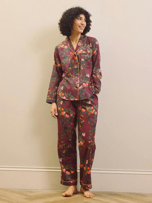 Woman wearing a burgundy floral pyjama set against a plain background