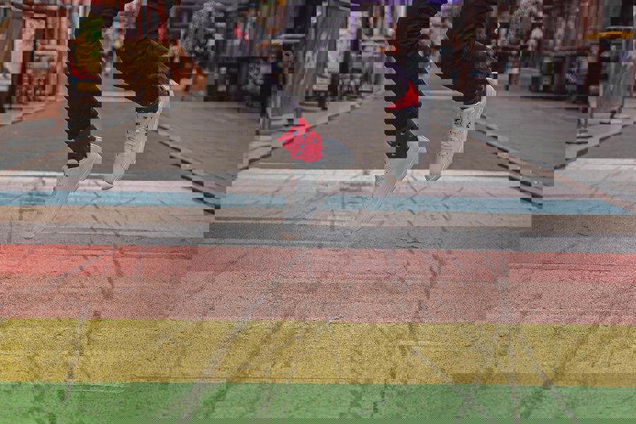 Person wearing red spotty socks and  jumping on a colorful crosswalk with blurred background