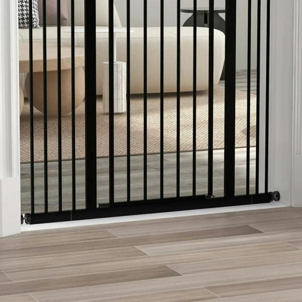 Black pressure-fit dog safety gate bottom rail with vertical bars at doorway threshold