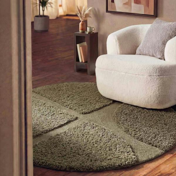Green shaggy rug in a living room with a white armchair and wooden floor.