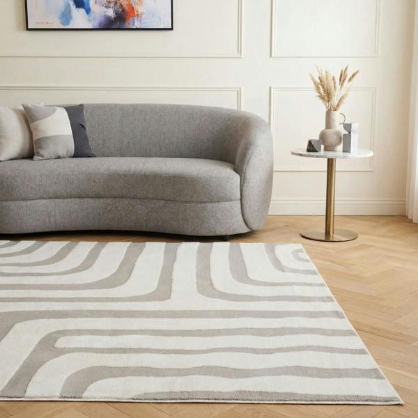 Living room with a gray sofa, abstract painting, and patterned rug.