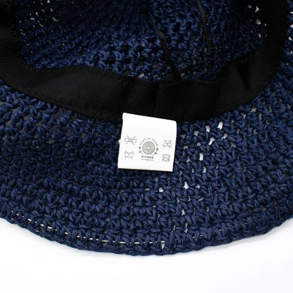Navy blue straw sun hat with black inner band and white Nomad label